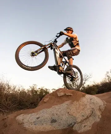 man going over a rock on an electric mountain bike