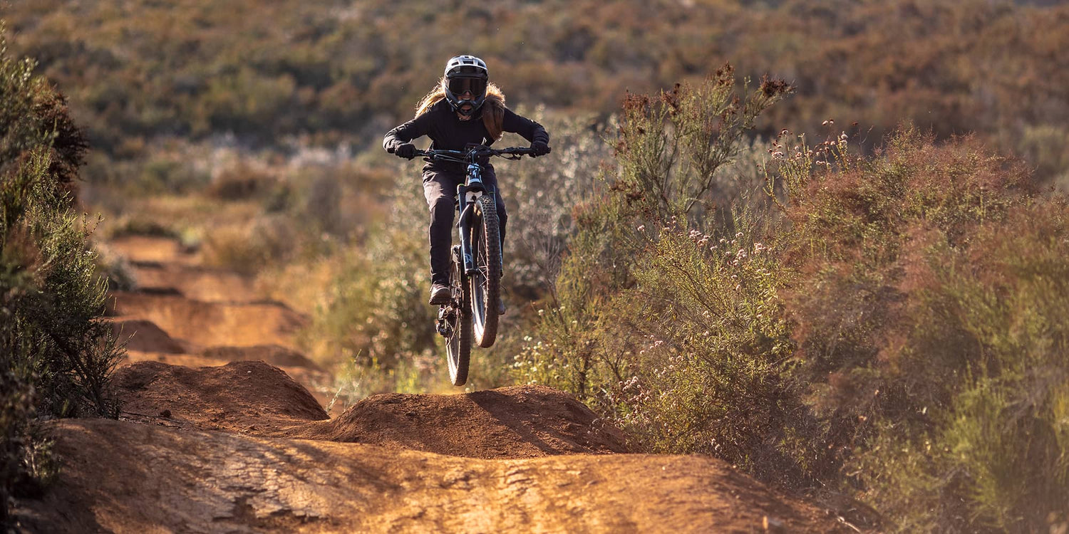 Woman riding electric Mountainbike doing a jump on a trail